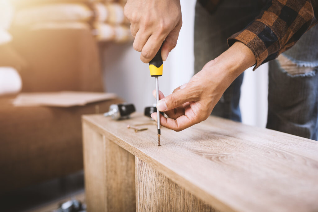 Mitarbeiter montiert ein Sideboard mit einem Schraubenzieher