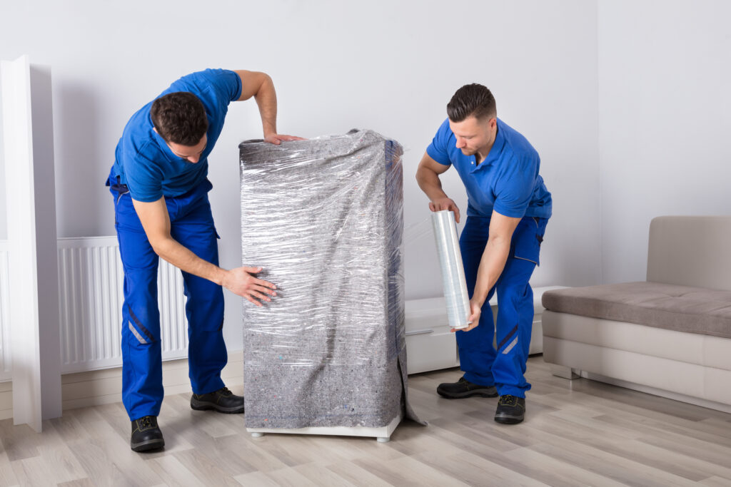 Zwei Mitarbeiter packen ein Möbelstück schonend ein