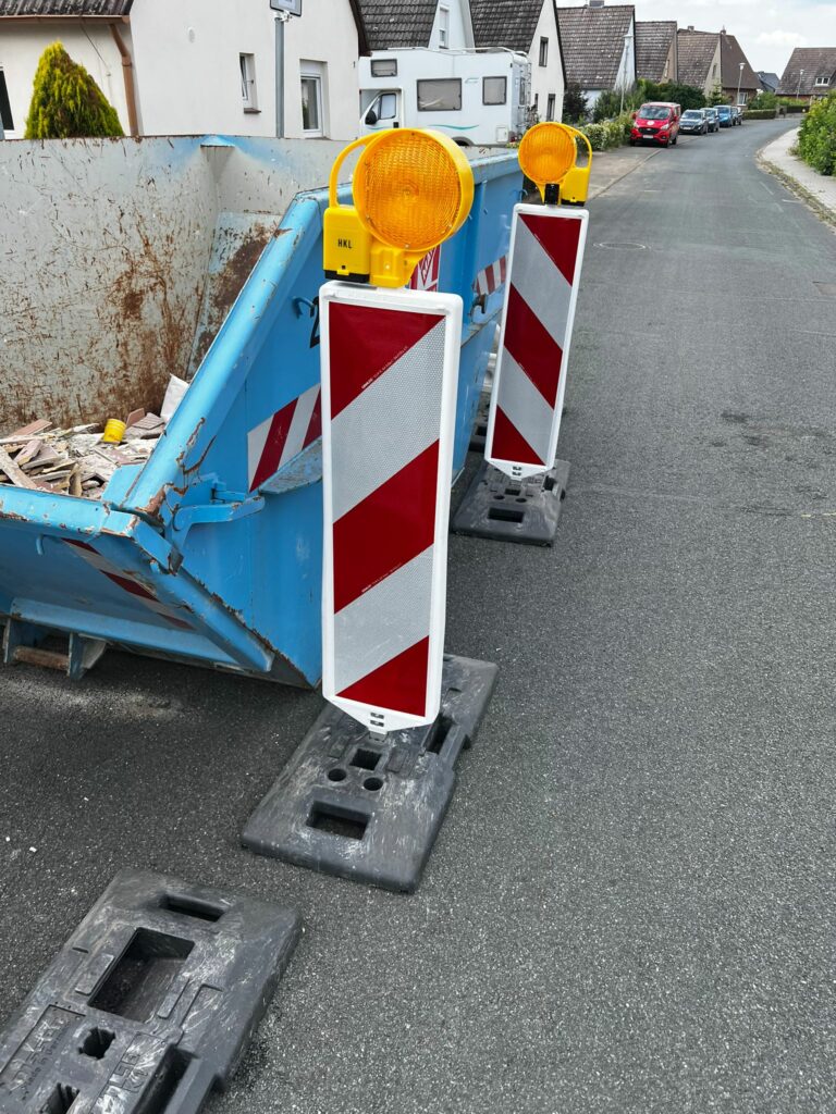 Schuttcontainer mit einer professionell eingerichteten Straßenabsperrung