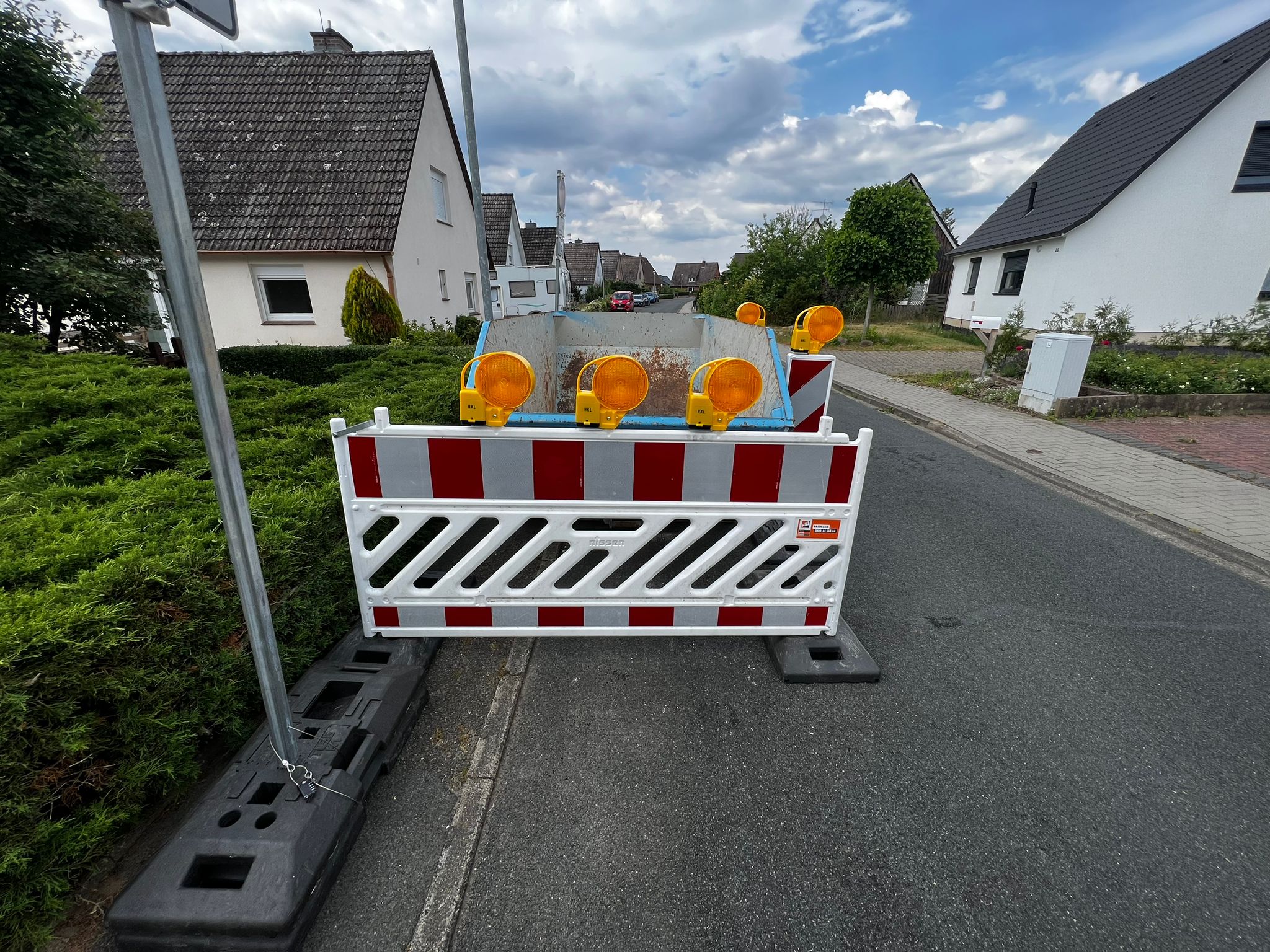 Container am Straßenrand mit professioneller Absperrung