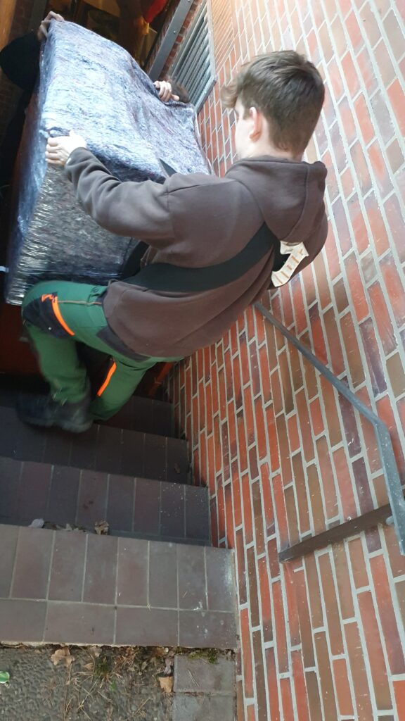 Transport einer Heimorgel über eine Kellertreppe durch Mitarbeiter von Martens Services